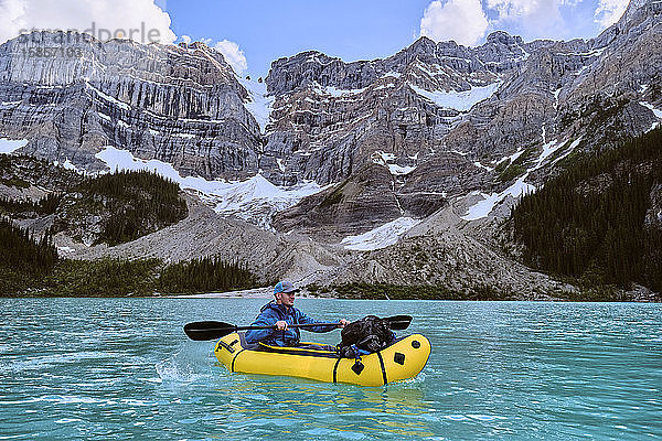 Abenteuerfotograf paddelt mit einem Packfloß über den Cirque Lake in Banff.