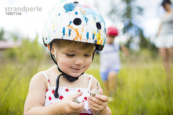 Junges Mädchen mit Helm geniesst Zeit beim Spielen im Freien