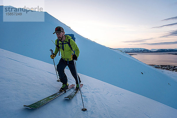 Mann Skitourenskifahren in Island bei Sonnenaufgang