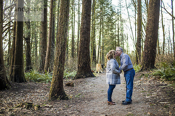 Ehepaar im Ruhestand küsst sich im Wald.