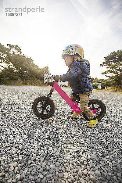 Seitenansicht eines einjährigen Mädchens auf rosa Fahrrad.