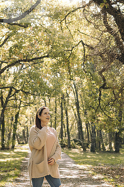 Junge braunhaarige Frau auf einer Straße mitten im Wald im Herbst