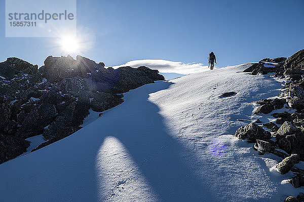 Figur  die einen Schneehang in den alpinen Bergen Neuseelands hinaufwandert