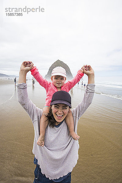 Glückliche Mutter lässt Tochter am Cannon Beach auf der Schulter reiten.