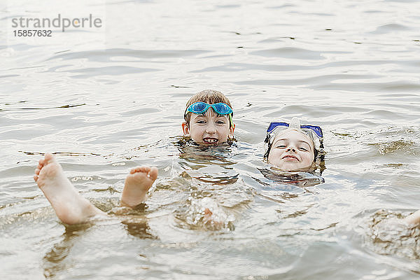Zwei Brüder mit Schutzbrille amüsieren sich im Wasser