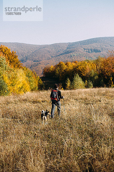 Mensch und Hund beim Wandern in herbstlicher Berglandschaft