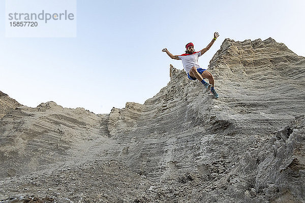 Ein Mann rennt auf einer sehr steilen Wand an einem alten Bergbauabfall aus Sand hinunter