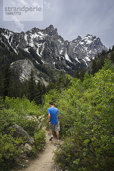 Mann wandert im Sommer auf einem Wanderweg im Teton-Gebirge