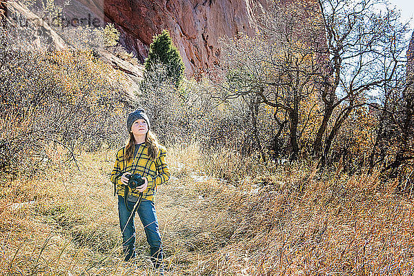 Junges Mädchen mit Kamera beim Wandern in den Bergen