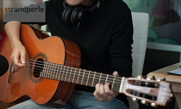 Frauenhände beim Spielen der akustischen Gitarre  Nahaufnahme.Konzept der Erholung