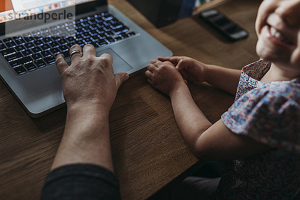 Nahaufnahme eines jungen Mädchens und eines Vaters  während er von zu Hause aus arbeitet