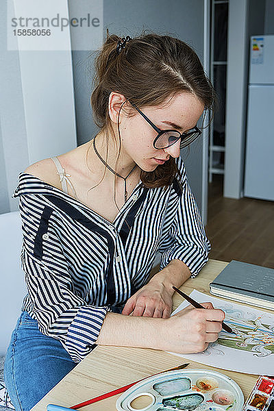 tausendjähriges Mädchen malt fabelhafte Bilder auf Papier  während sie zu Hause sitzt