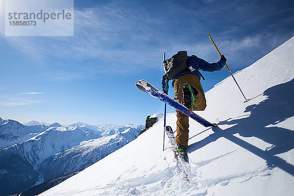 Skitourengeher bei einer Bergauf-Kick-Kurve mit Bergkulisse