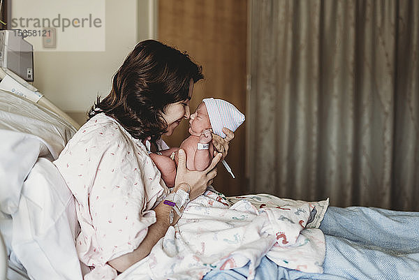 Seitenansicht der Mutter und des neugeborenen Sohnes beim Berühren der Nasen im Krankenhaus