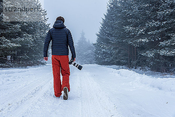 Fotograf  der im Winter im Wald fotografiert.