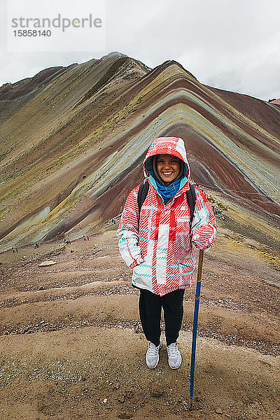 Eine junge Frau steht auf dem berühmten Regenbogenberg in Peru