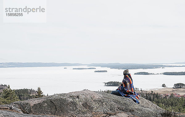 Frau  die auf einem Felsen sitzt und einen schönen Blick auf Schweden hat