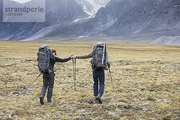 Zwei Rucksacktouristen (Freunde) stoßen während der Fahrt über den Arktispass mit der Faust zusammen