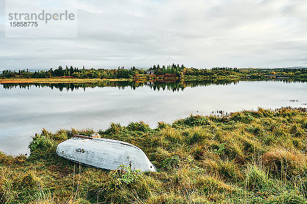 Landschaft mit einsamen Seeufern und umgestürztem Boot auf dem Land
