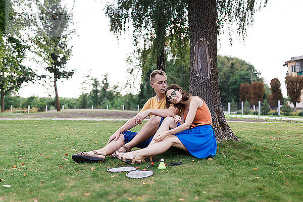 Tausendjähriges Ehepaar sitzt im Gras  nachdem es im Park Badminton gespielt hat