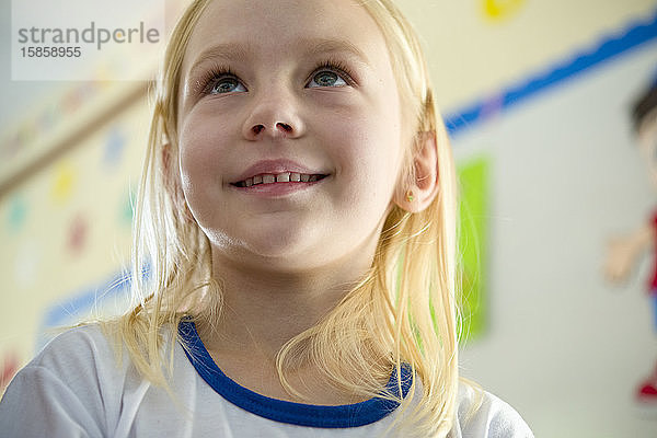 Süßes kleines blondes Mädchen in der Schule  lächelnd