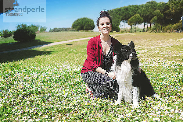 Schöne Frau mit Hund in einem Park mit Blick in die Kamera
