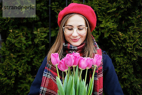 junges französisches tausendjähriges Mädchen in Baskenmütze und Mantel mit Tulpen in den Händen