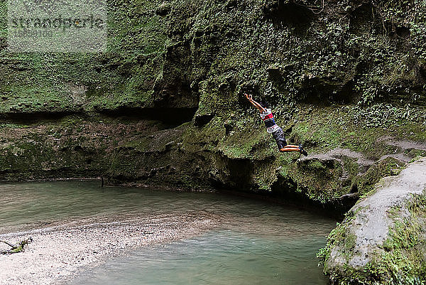 Junge springt von Klippe ins Wasser