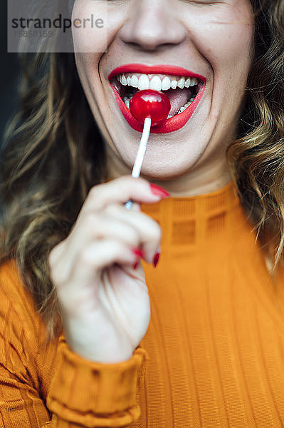 Hübsche Frau mit roten Lippen isst ein Bonbon