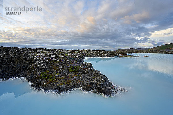 Malerische Landschaft mit blauem See und felsiger Küste bei bewölktem Himmel