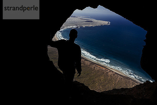 Silhouette eines Mannes aus einer Höhle auf der Klippe von Famara auf Lanzarote  Spanien