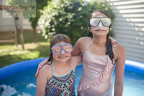 Mädchen zwischen 10 und 12 Jahren tragen eine Schwimmbrille und legen ihre Arme umeinander