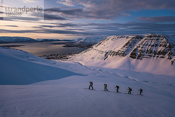 Personengruppe beim Skilanglauf bei Sonnenaufgang in Island