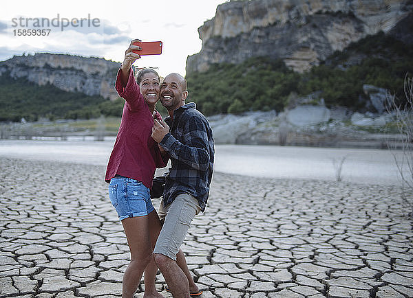Paar  das während einer Reise am Ufer eines Sees ein Selfie macht.