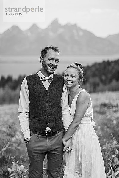 Schwarz-Weiß von glücklich lächelndem Brautpaar vor den Bergen
