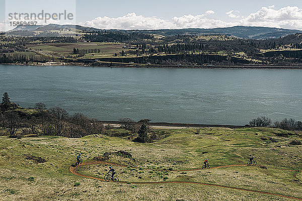 Eine Gruppe von Mädchen fährt mit dem Fahrrad einen Weg entlang  der den Columbia River überblickt.