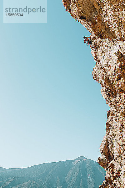 Rückansicht eines männlichen Kletterers an der Wand mit El Teide im Rücken