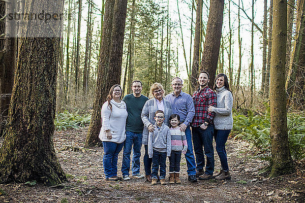 Glückliche Familie steht für ein Foto in einem bewaldeten Park.