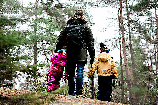 Papa steht mit seinen Kindern im Winter beim Wandern im Freien