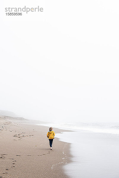 Teenager spaziert am Ozeanrand am ruhigen Strand entlang
