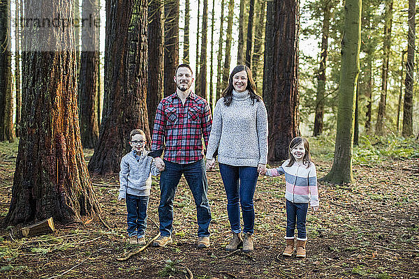 Familie an den Händen haltend  im Wald stehend.