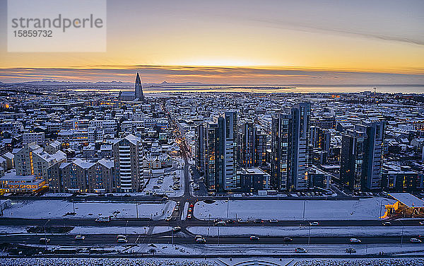 Verschneite Stadtstraßen und Wohnhäuser bei Sonnenuntergang