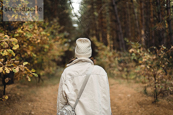 Rückenansicht einer nicht erkennbaren Frau im Wald.