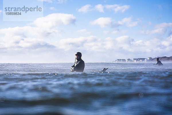 Mann surft arktisch kalten Wintersurf-Tag mit Meeresrauch