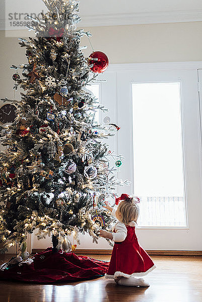 Junges Mädchen betrachtet Ornamente am Weihnachtsbaum
