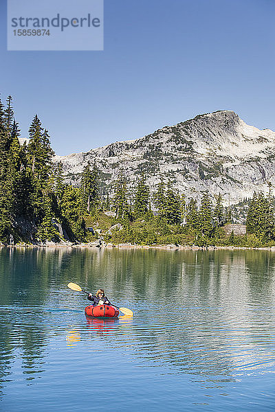 Pensionierte Frau paddelt auf einem abgelegenen Bergsee.