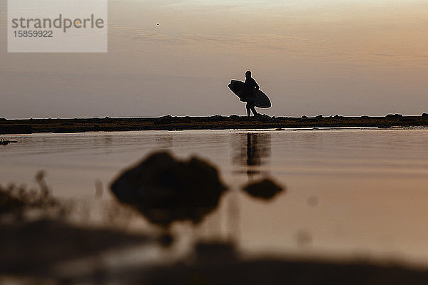 Silhouette eines Surfers bei Sonnenuntergang am Strand