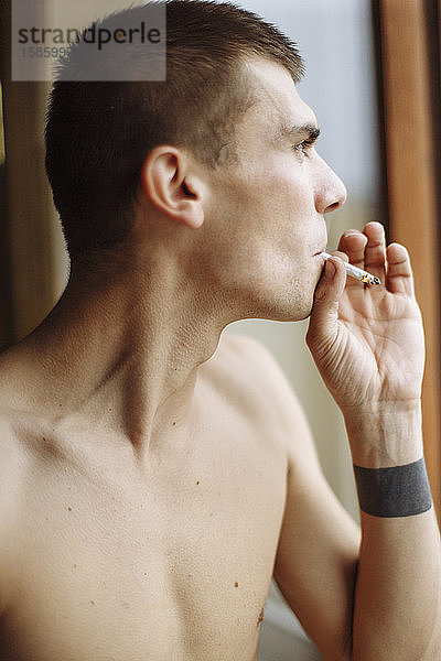 Ein Seitenprofil Nahaufnahme-Portrait eines jungen Mannes  der eine Zigarette raucht