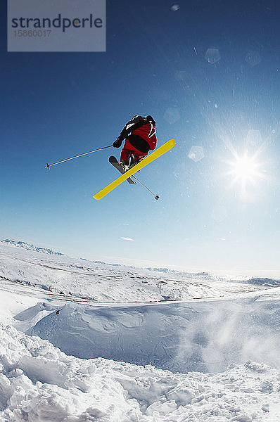 Skifahrer springt von verschneiter Piste in Island