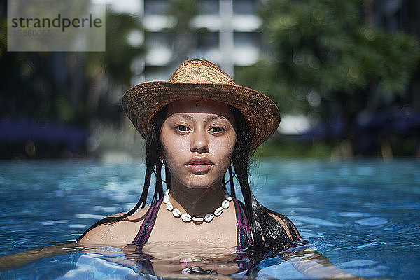 Stylisches  trendiges  junges Teenager-Viscomädchen im Pool mit Strohhut